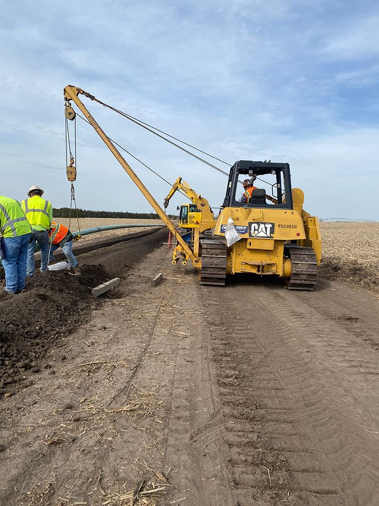 A tractor on a dirt road next to a crane