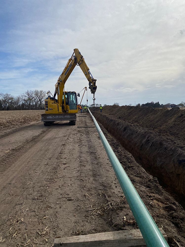 A yellow excavator digging a trench