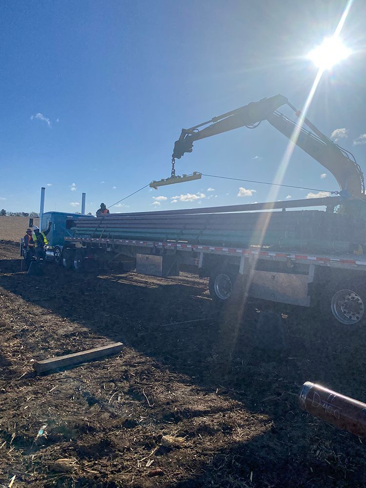 A crane is lifting a piece of metal on top of a truck