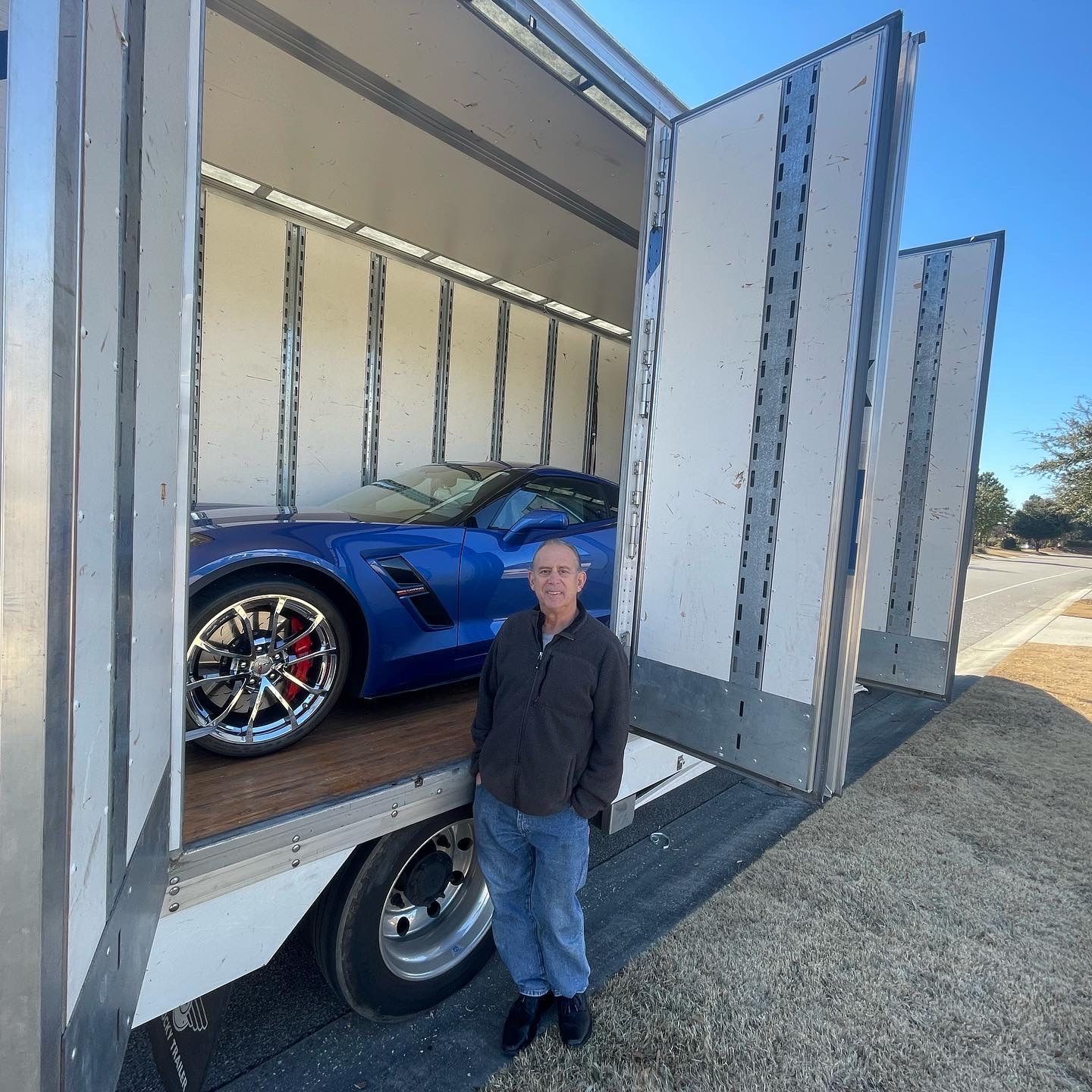 A group of people are working on a wooden structure in front of a house.