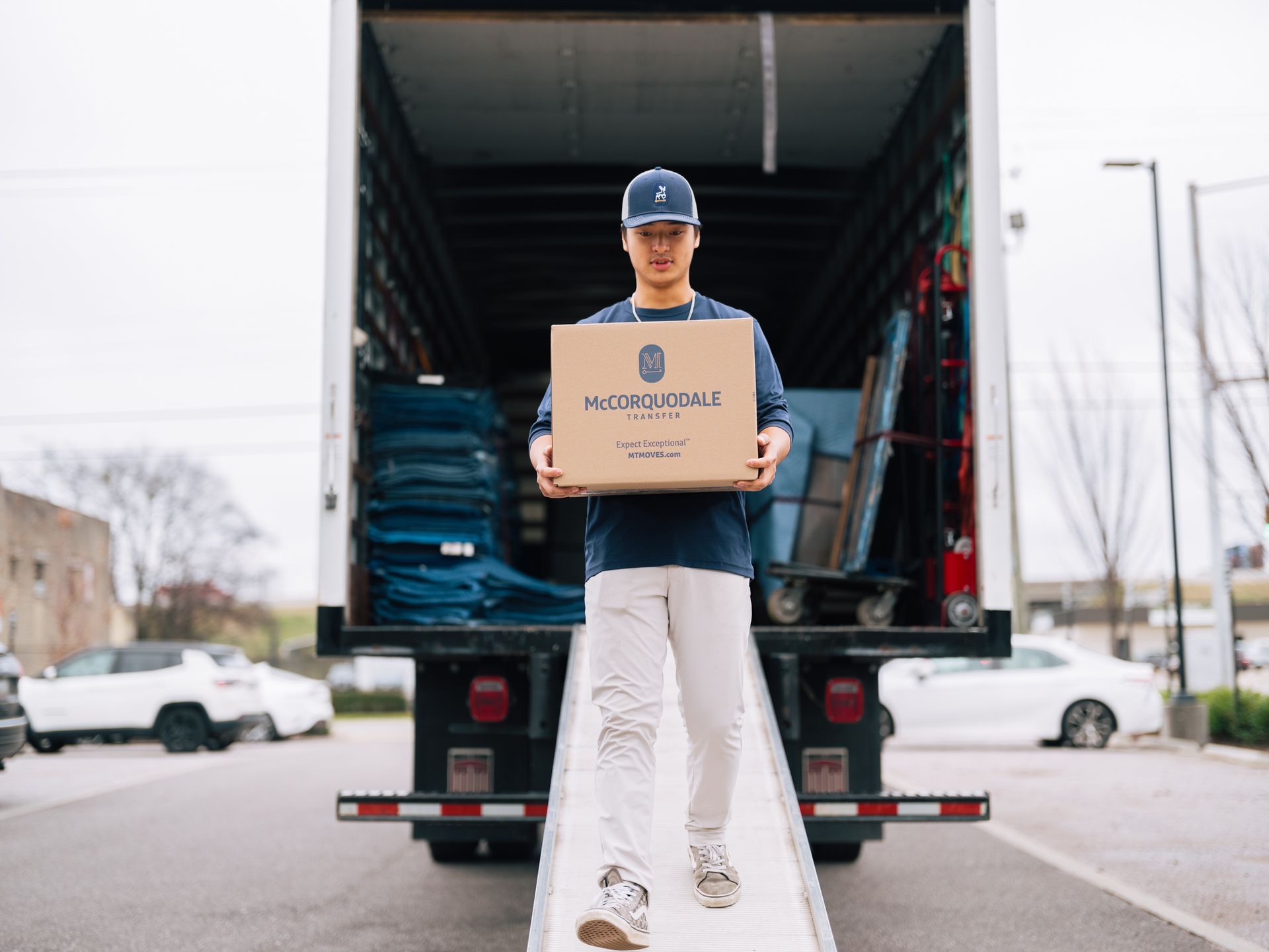 Person carrying box down ramp from moving truck.