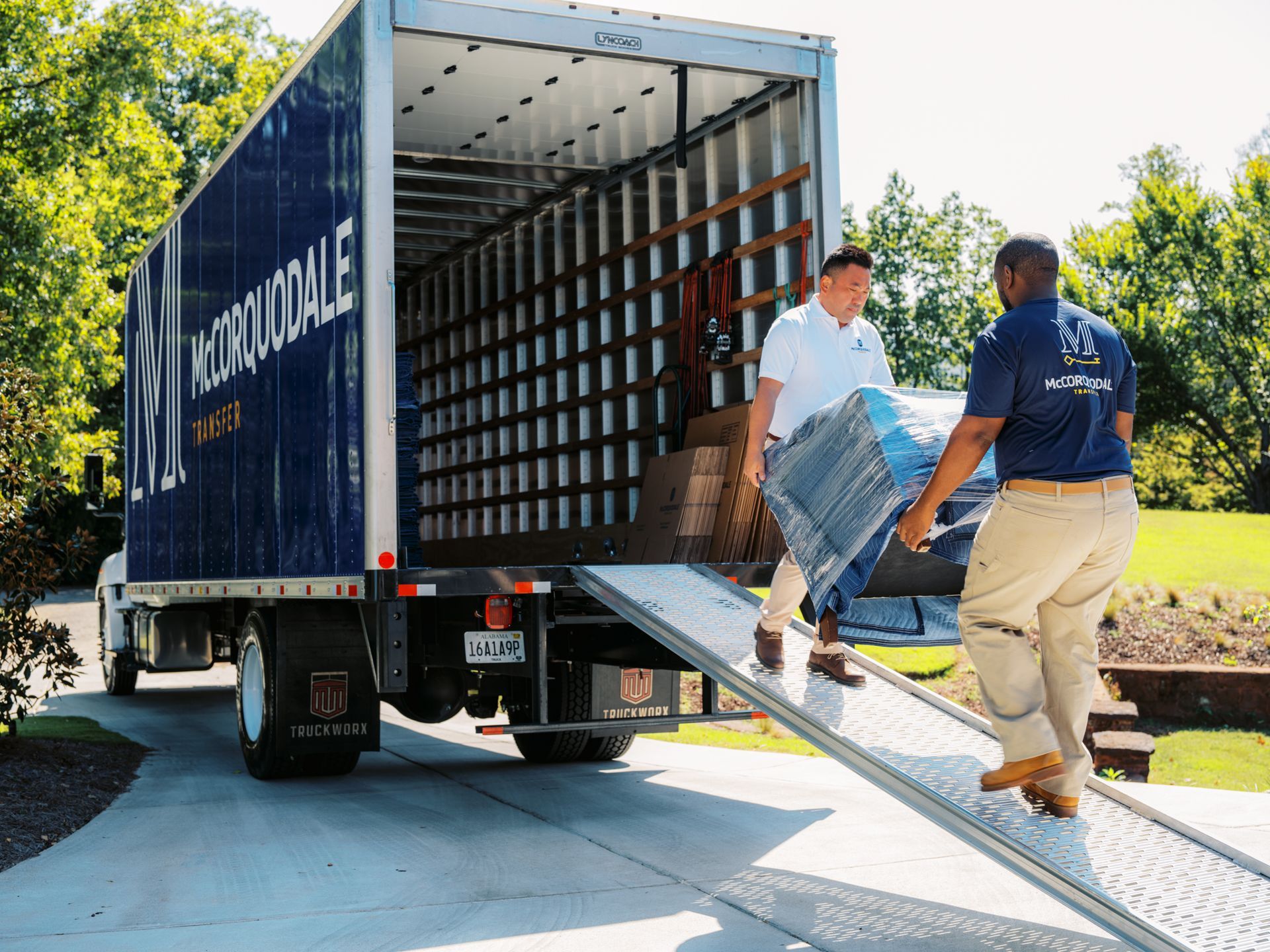 Movers loading furniture into a moving truck on a driveway.