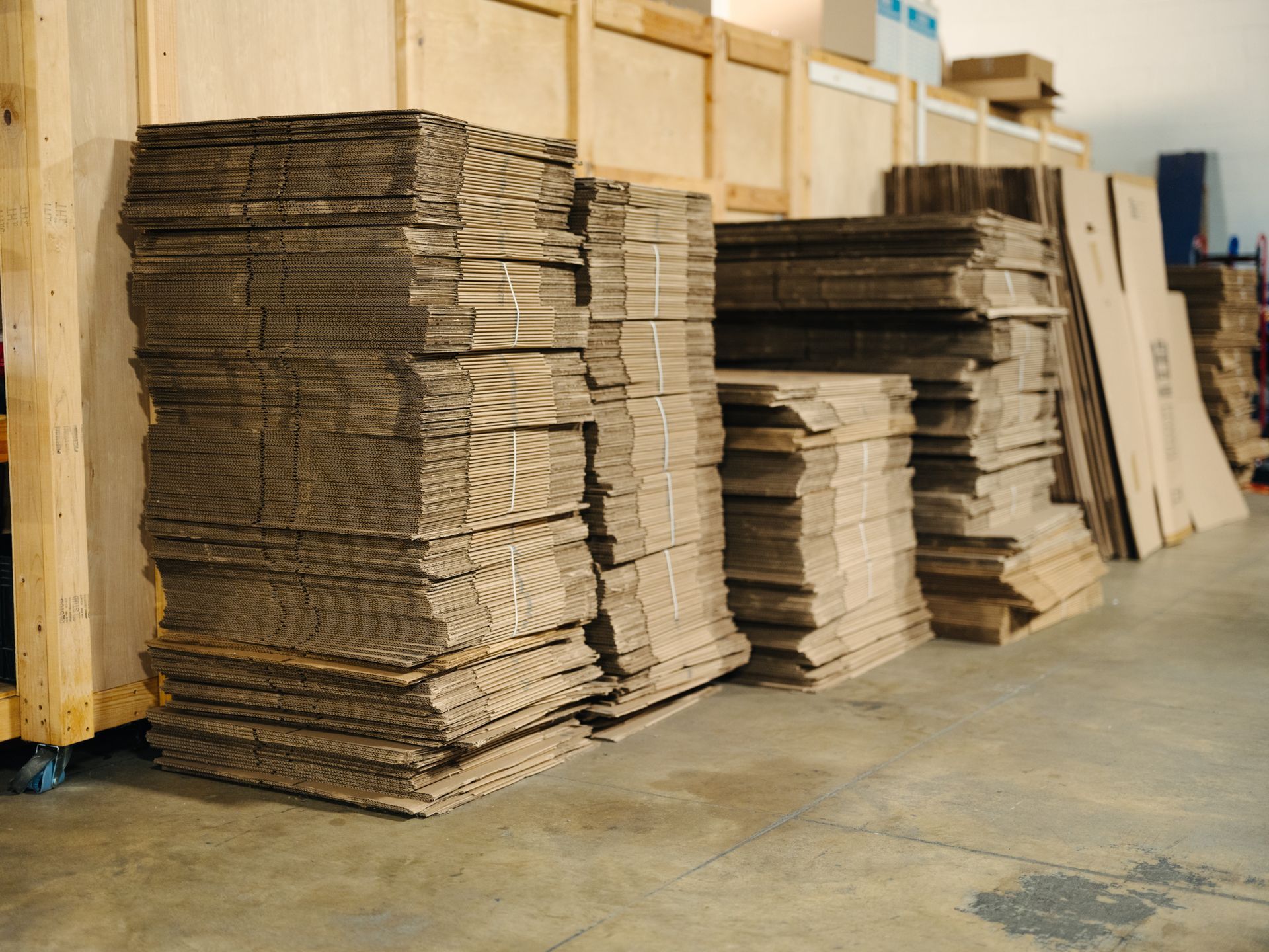 Stacks of flattened cardboard boxes in a warehouse setting.