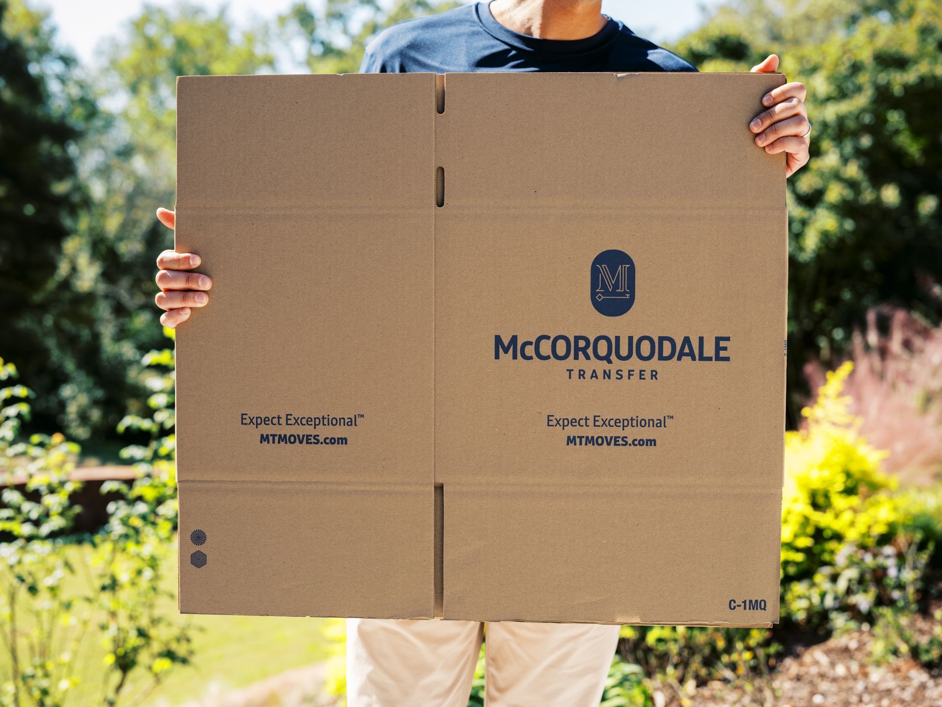 Person holding a large cardboard box with the
