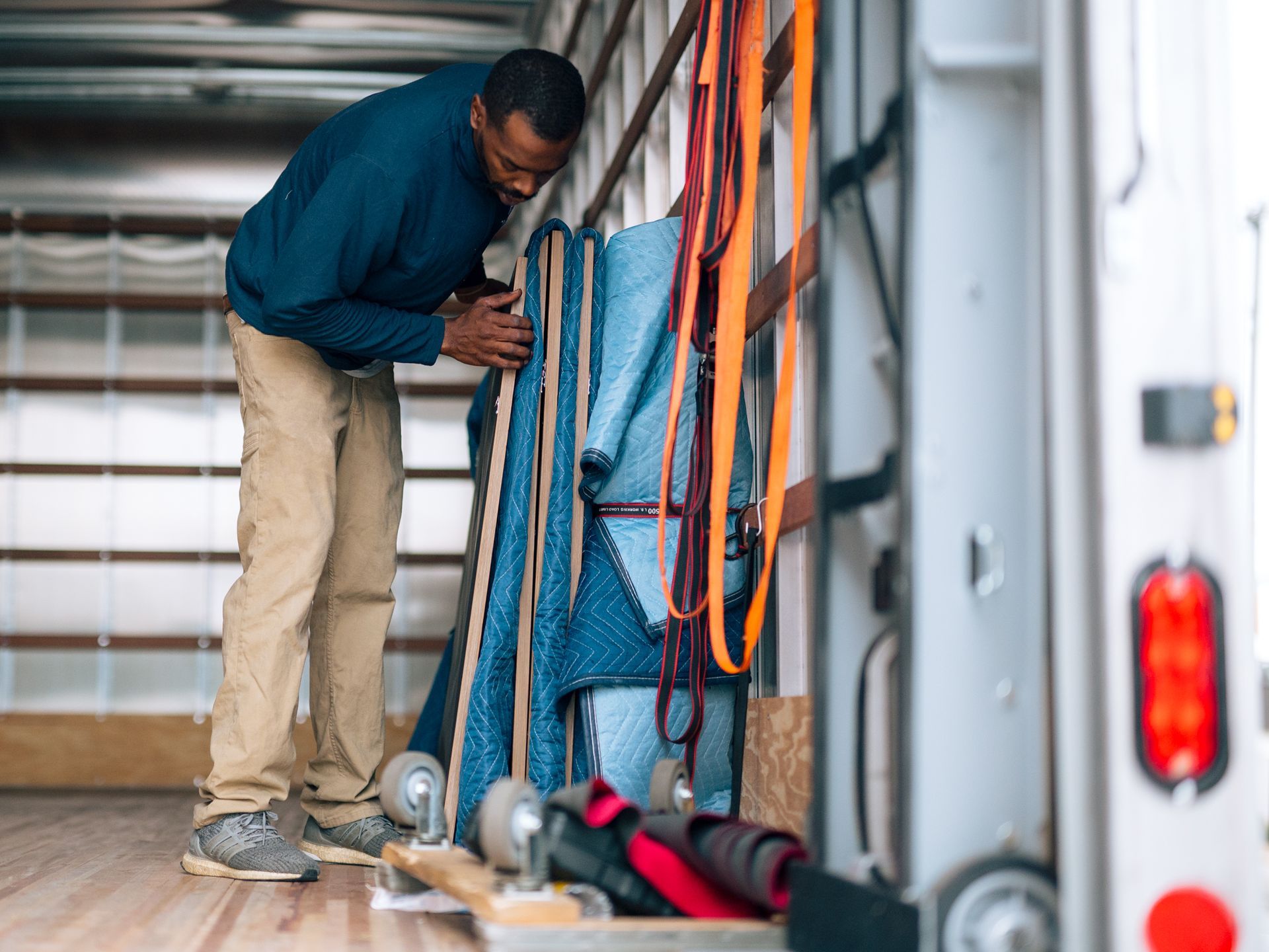 Man inside truck arranging items: rugs, straps, and tools.