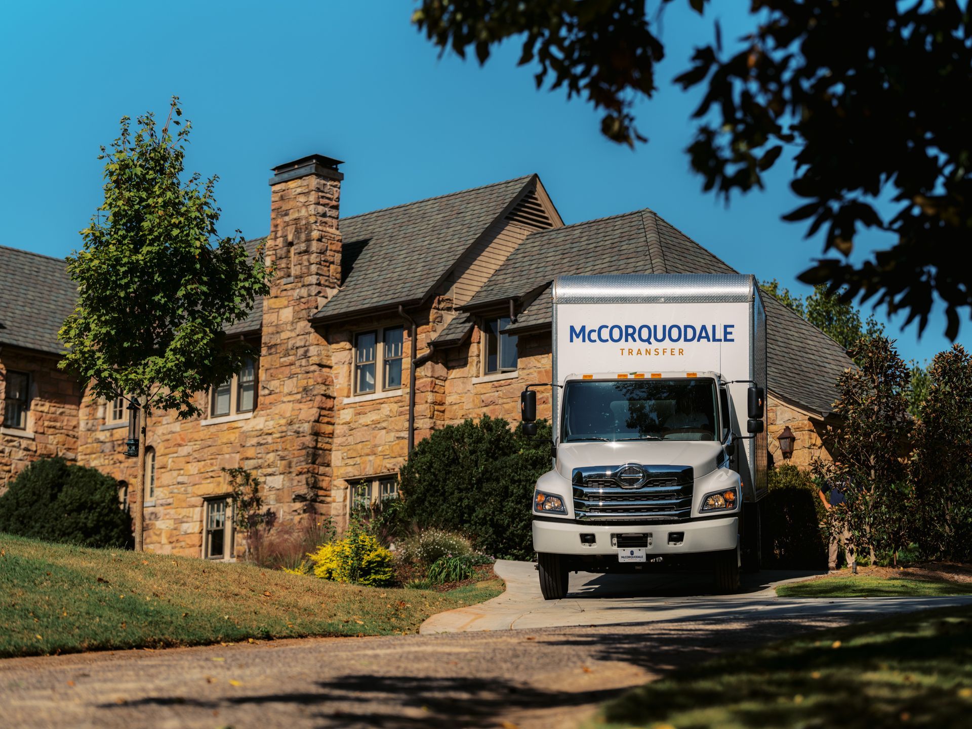 Moving truck in front of a large stone house. The truck is labeled