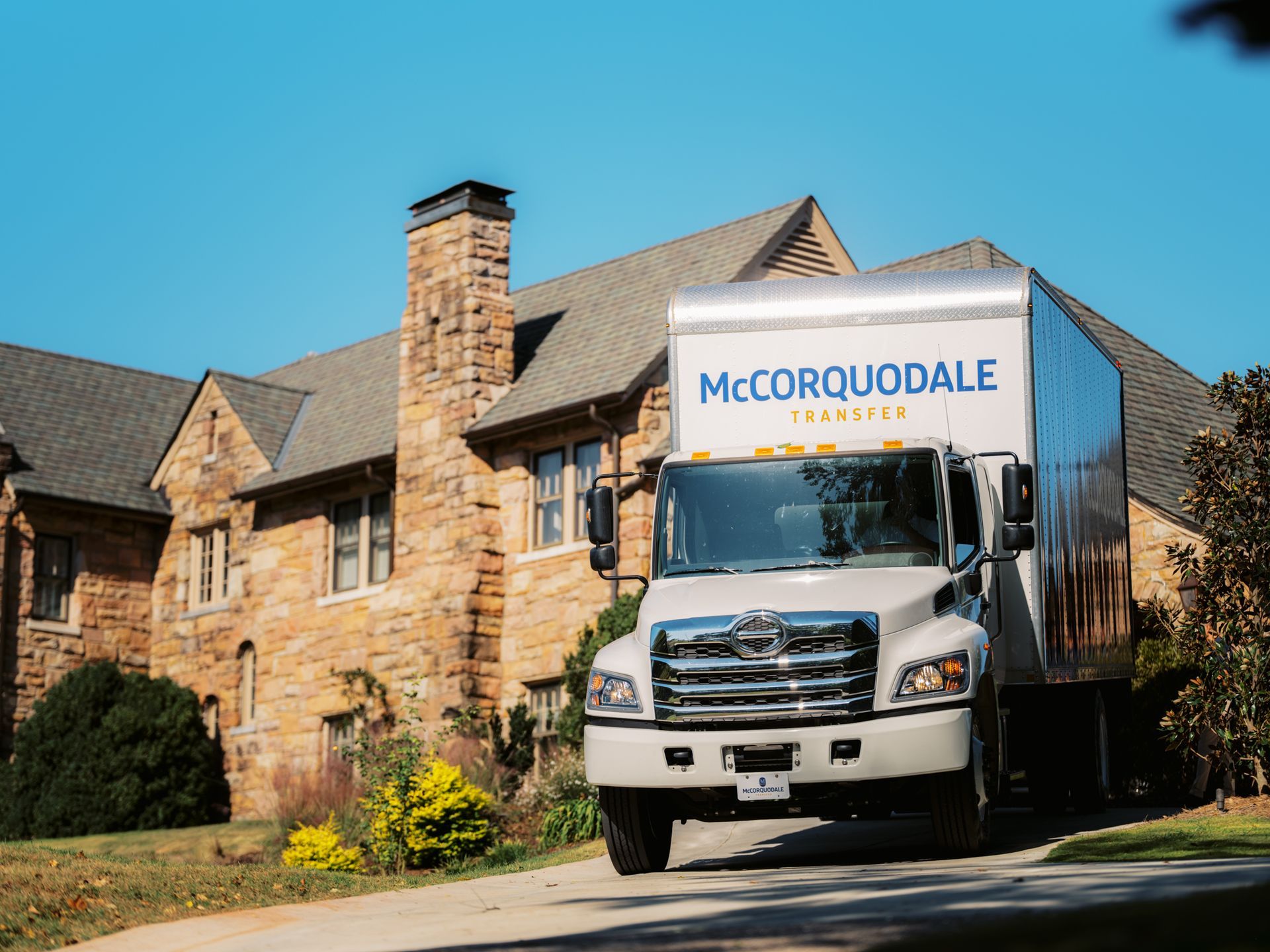 Moving truck in front of a stone house;