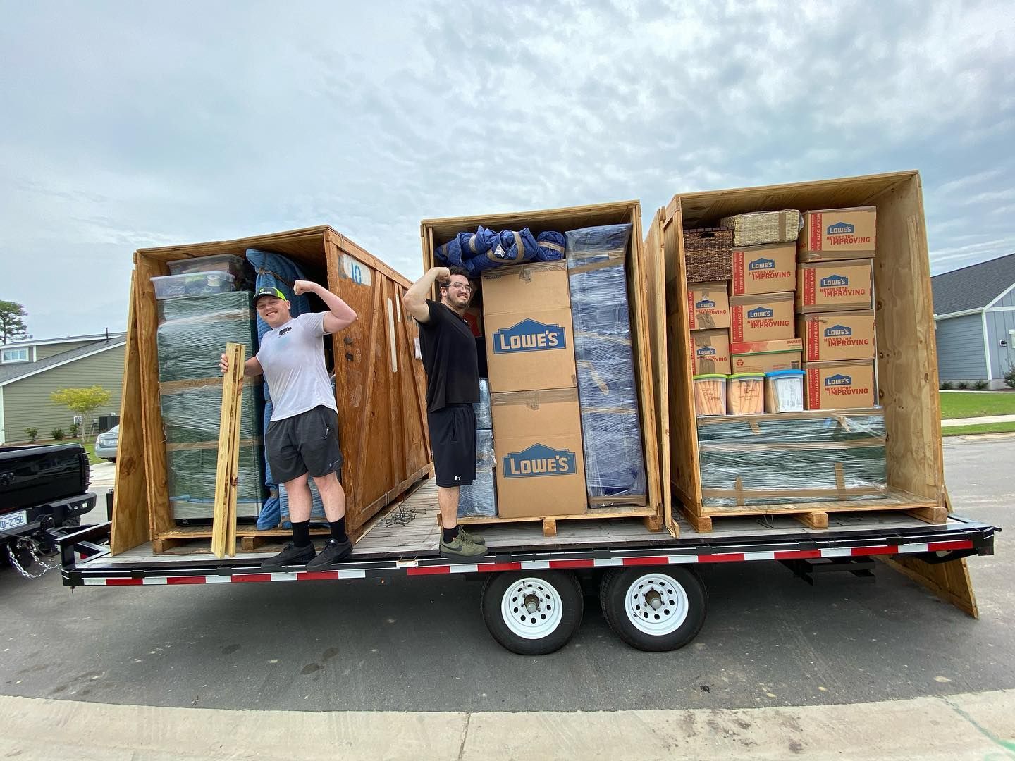 Two men are loading boxes onto a trailer.