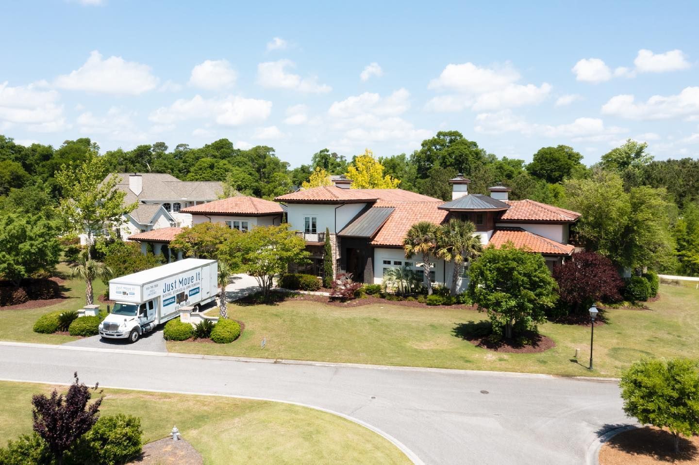 An aerial view of a large house with a moving truck parked in front of it.