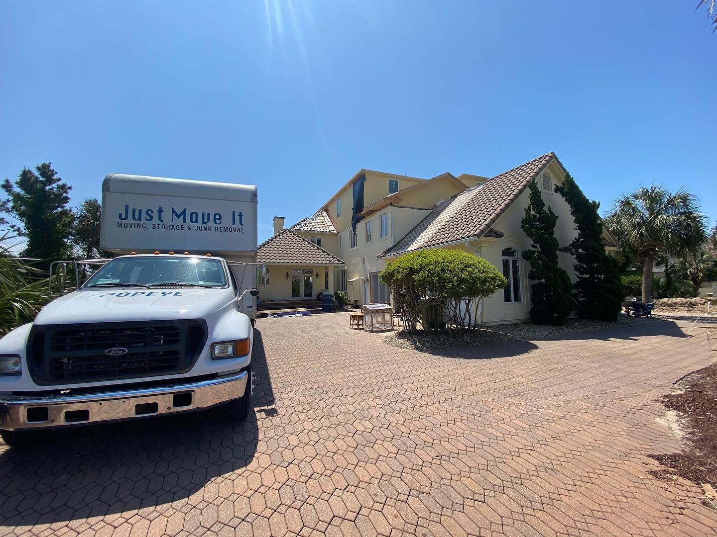 A just move it truck is parked in front of a large house