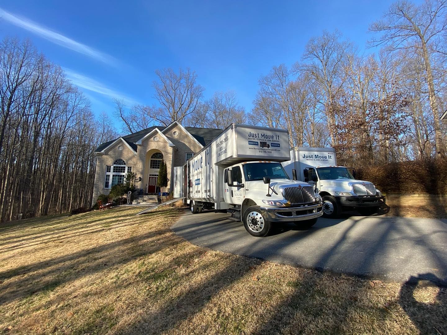 Two moving trucks are parked in front of a house.