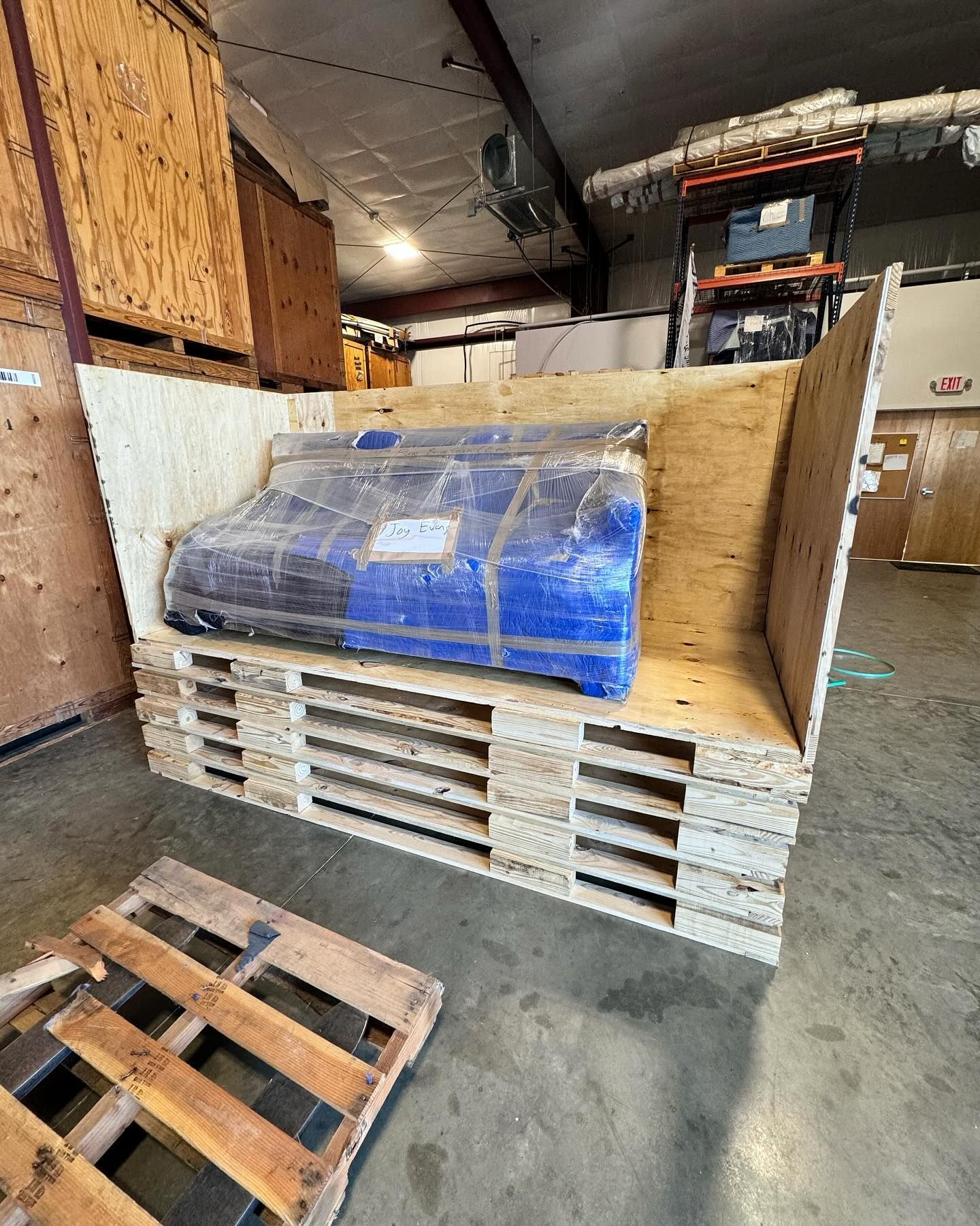 A blue box is sitting on top of a wooden pallet in a warehouse.