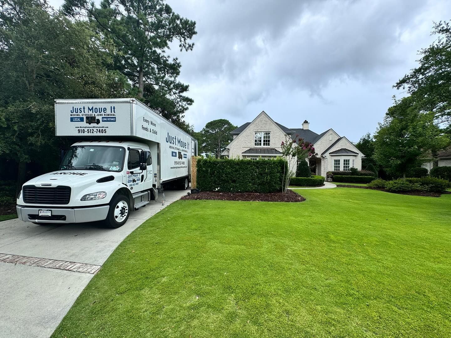 A moving truck is parked in front of a large house.