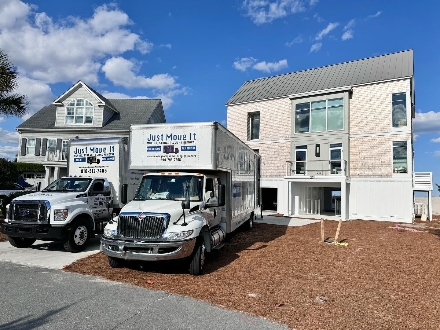 Two moving trucks are parked in front of a house.
