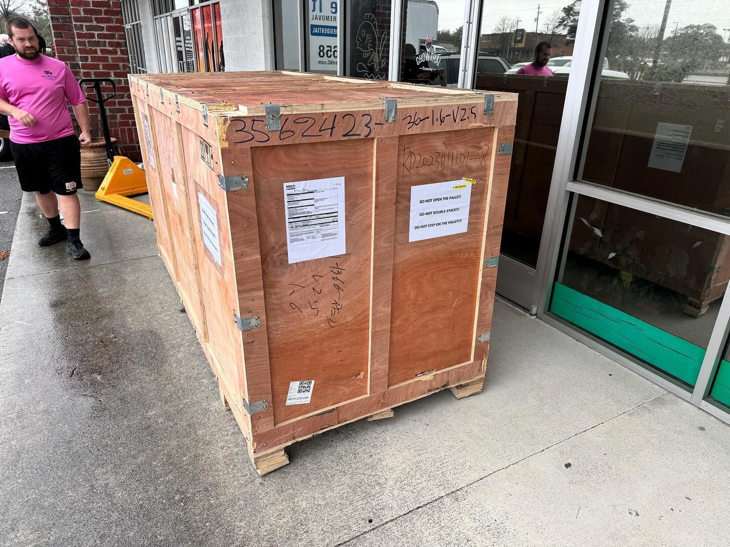 A large wooden box is sitting outside of a store.