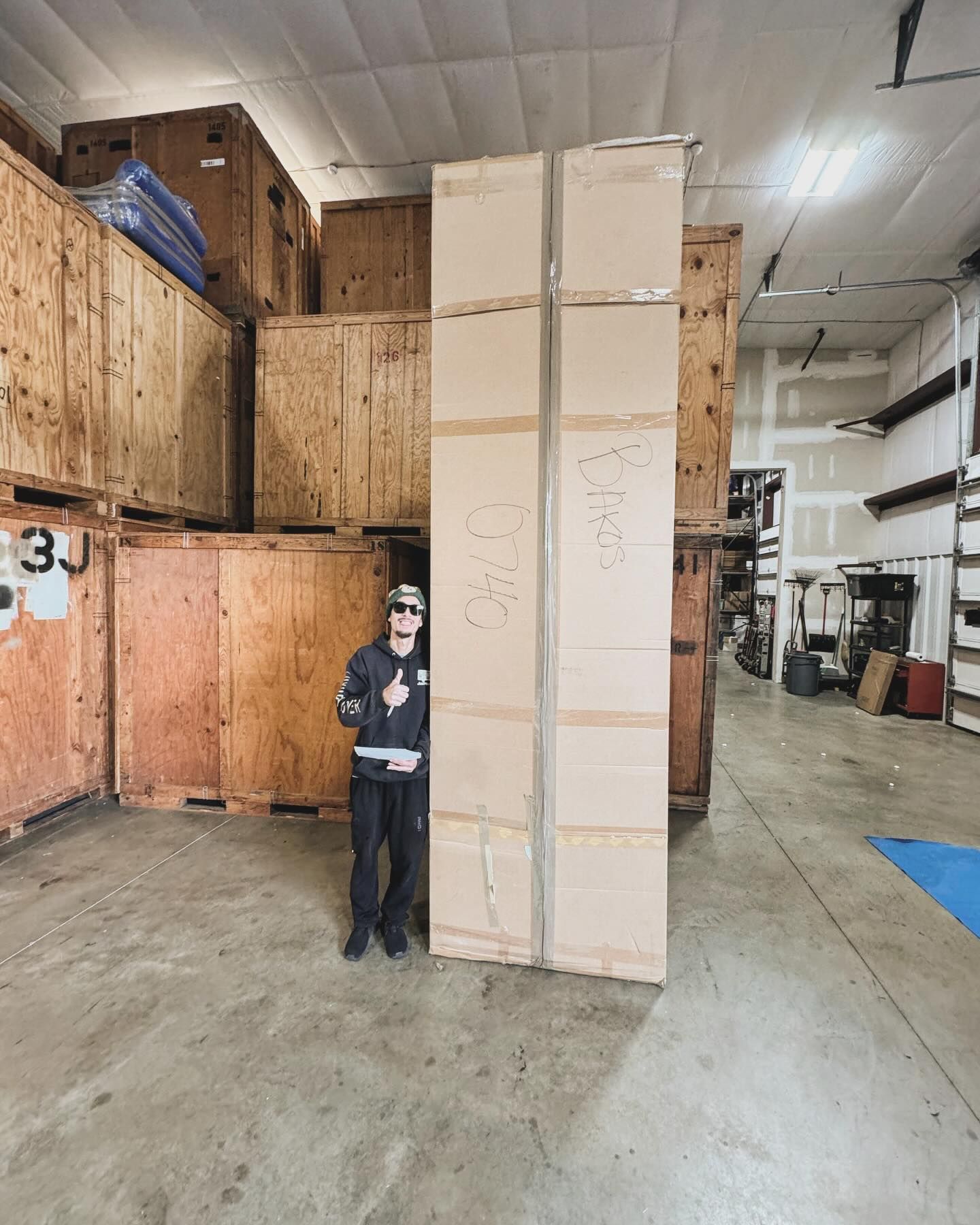 A man is standing next to a large box in a warehouse.