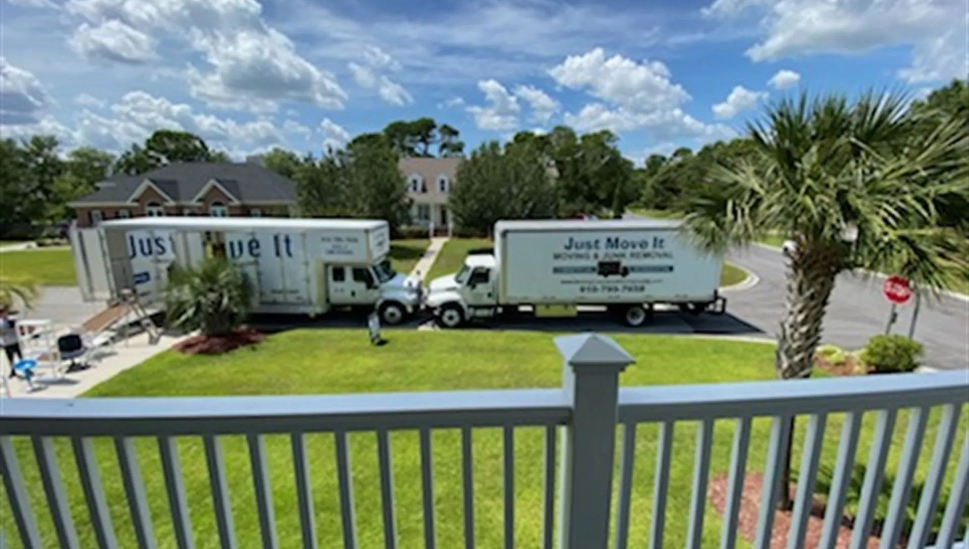 Two just move it trucks are parked in front of a house