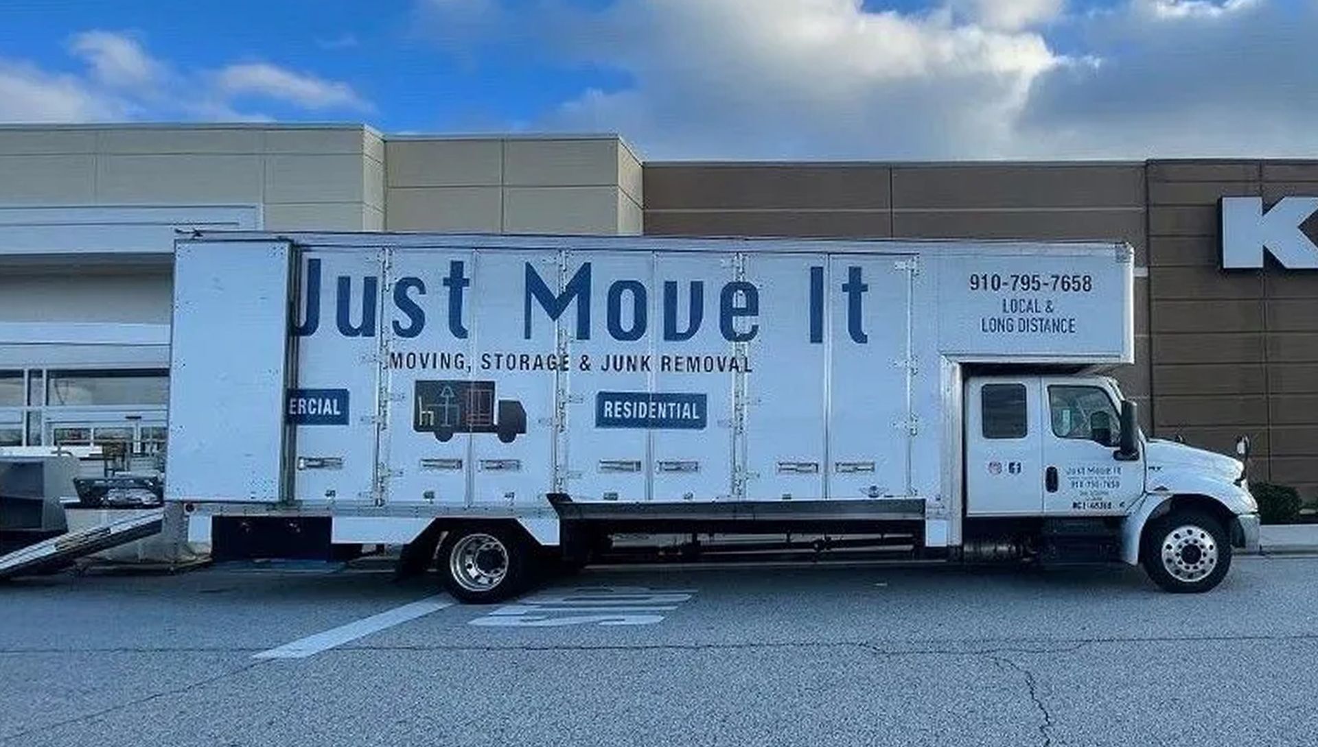 A white moving truck is parked in front of a store