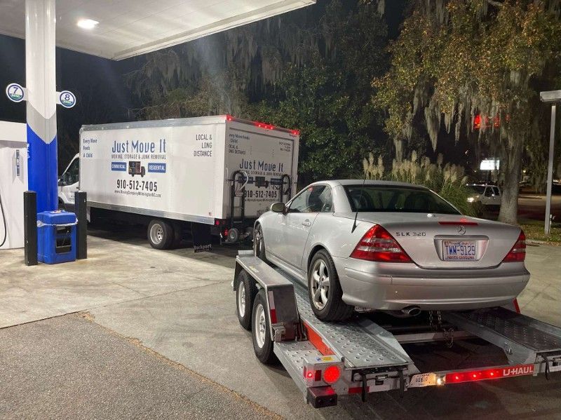 A car is being towed by a truck at a gas station.