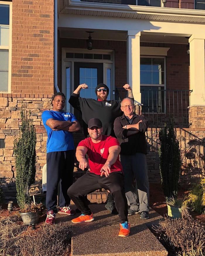 A group of men are posing for a picture in front of a brick house.