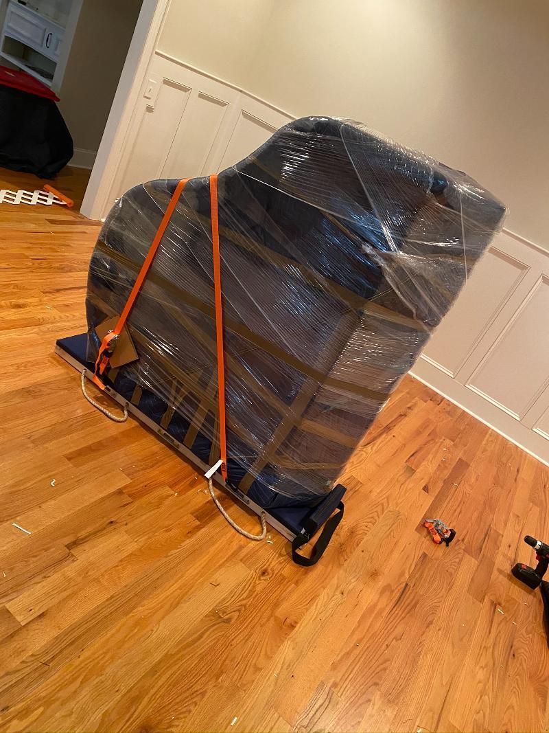 A piano is wrapped in plastic and sitting on top of a wooden floor.