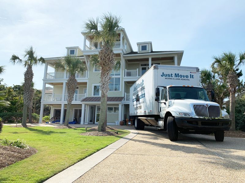 A moving truck is parked in front of a large house.