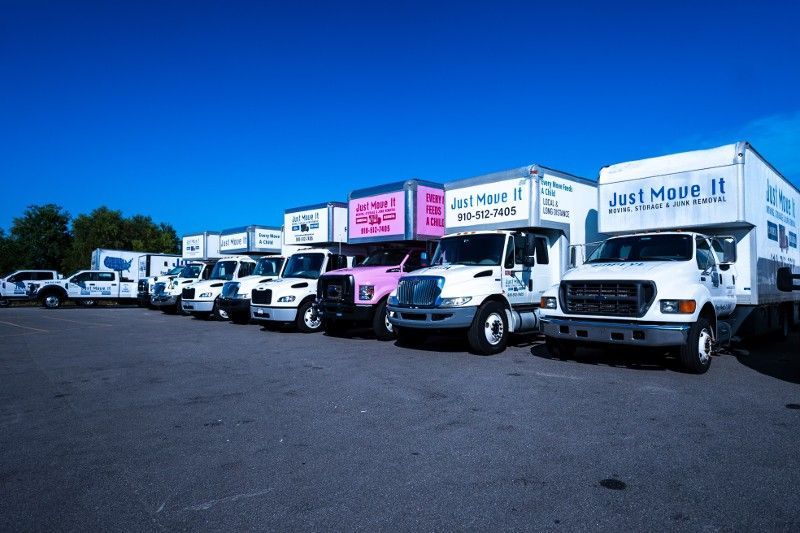 A row of moving trucks are parked in a parking lot.