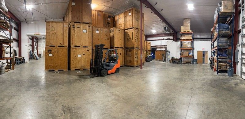 A forklift is driving through a large warehouse filled with lots of boxes.