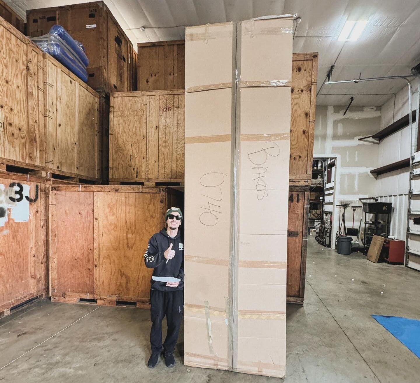 A man is standing next to a large box in a warehouse.