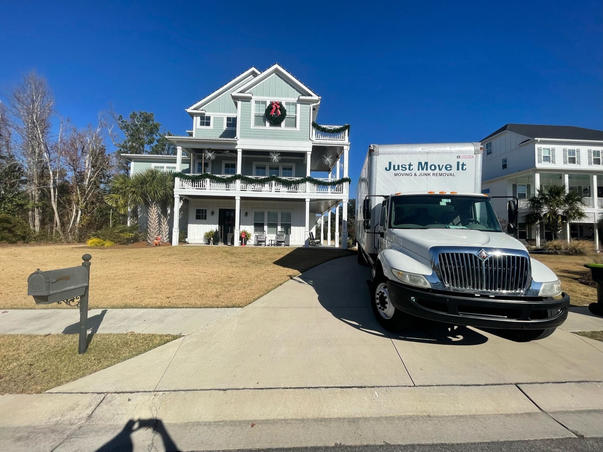 Two-story white house with a black SUV parked in the driveway under a clear blue sky