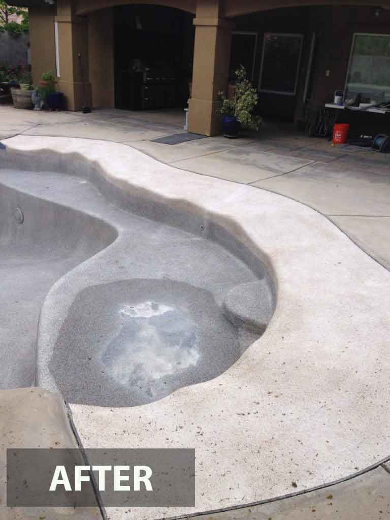Renovated concrete pool with a gray interior and textured edge, viewed outdoors under daylight.