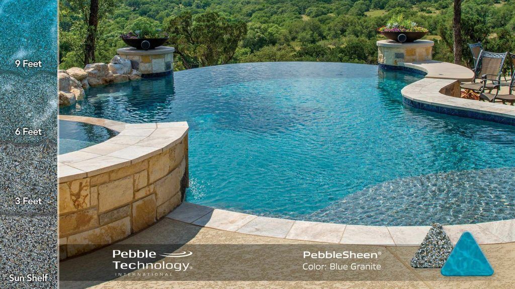 An infinity pool overlooking a wooded area. The pool has blue water, stone accents, and two fire bowls.