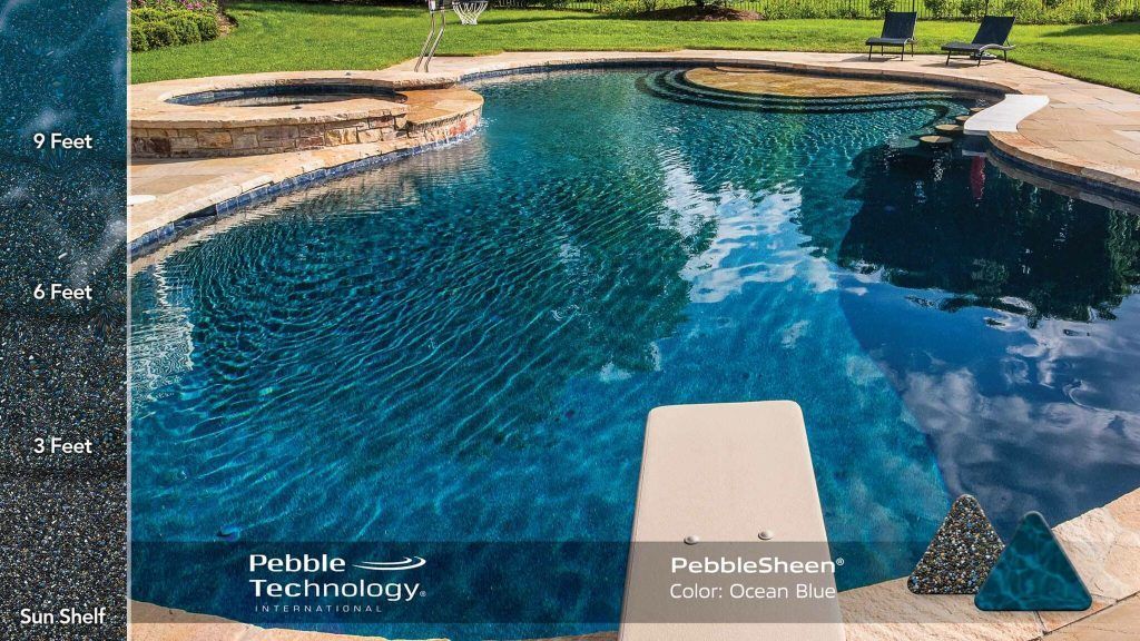 A dark blue pool with diving board, a jacuzzi and stone border.