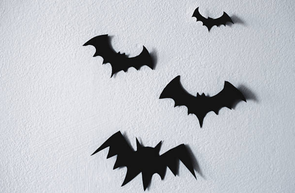 Black bat cutouts on a white wall, Halloween decorations.