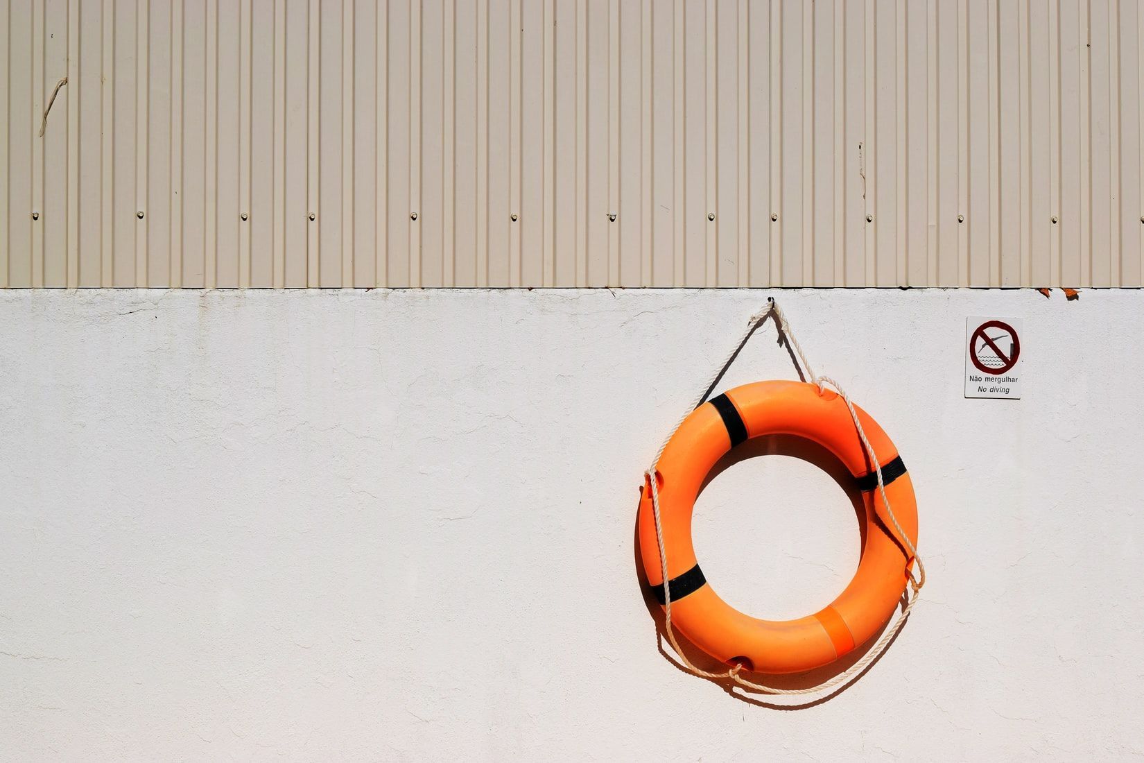 Orange life preserver hanging on a white wall under a beige panel with a