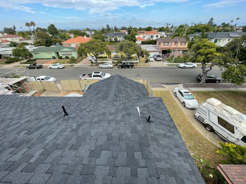 An aerial view of a roof in a residential area with cars parked on the side of the road.