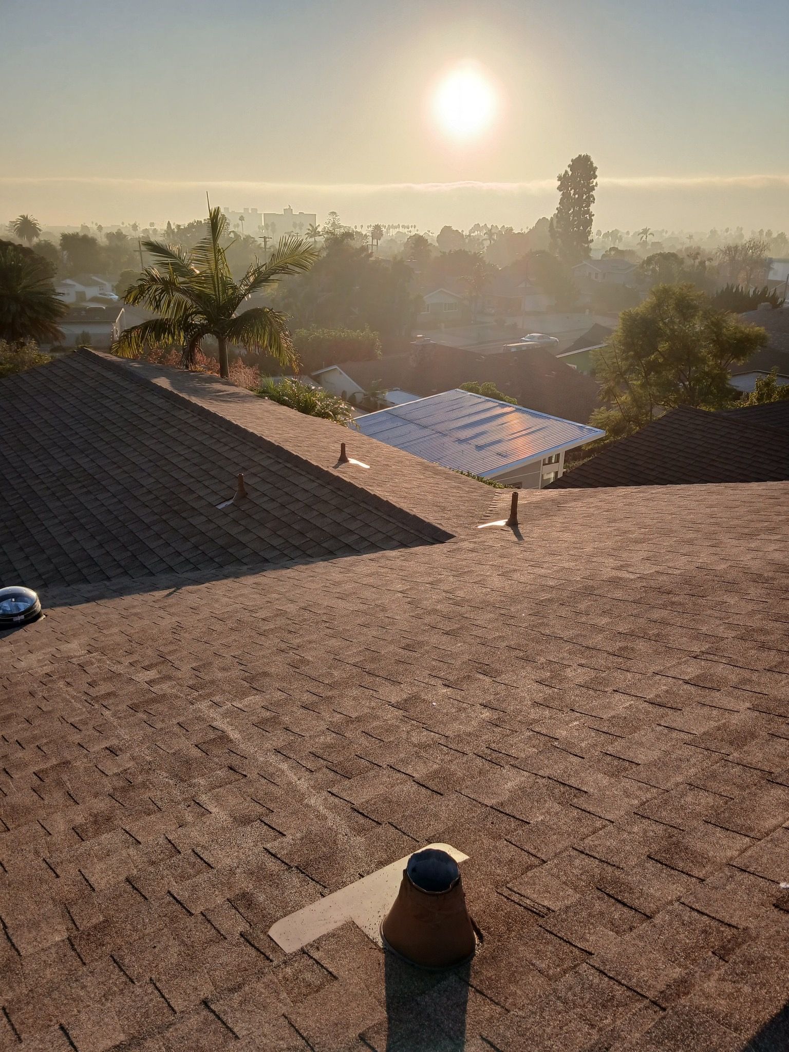 A rooftop view of a house with a sunset in the background.