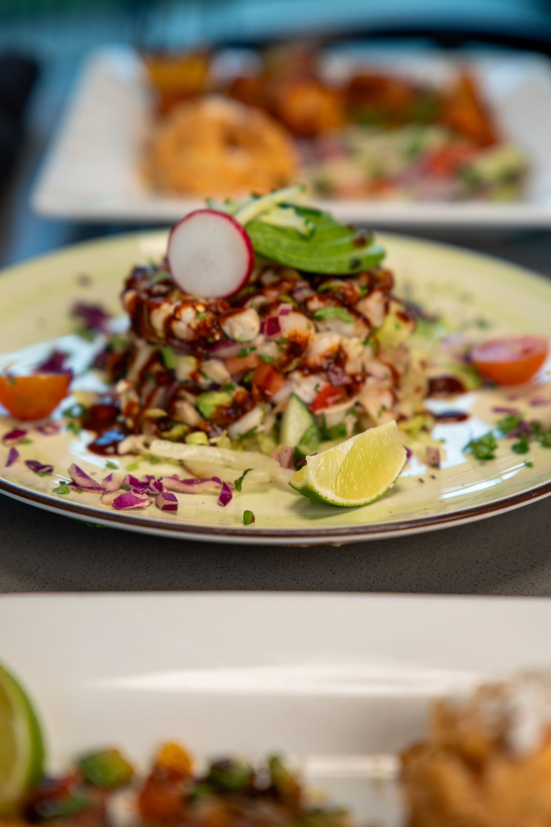 Stack of ceviche with avocado, lime, and radish on a plate.
