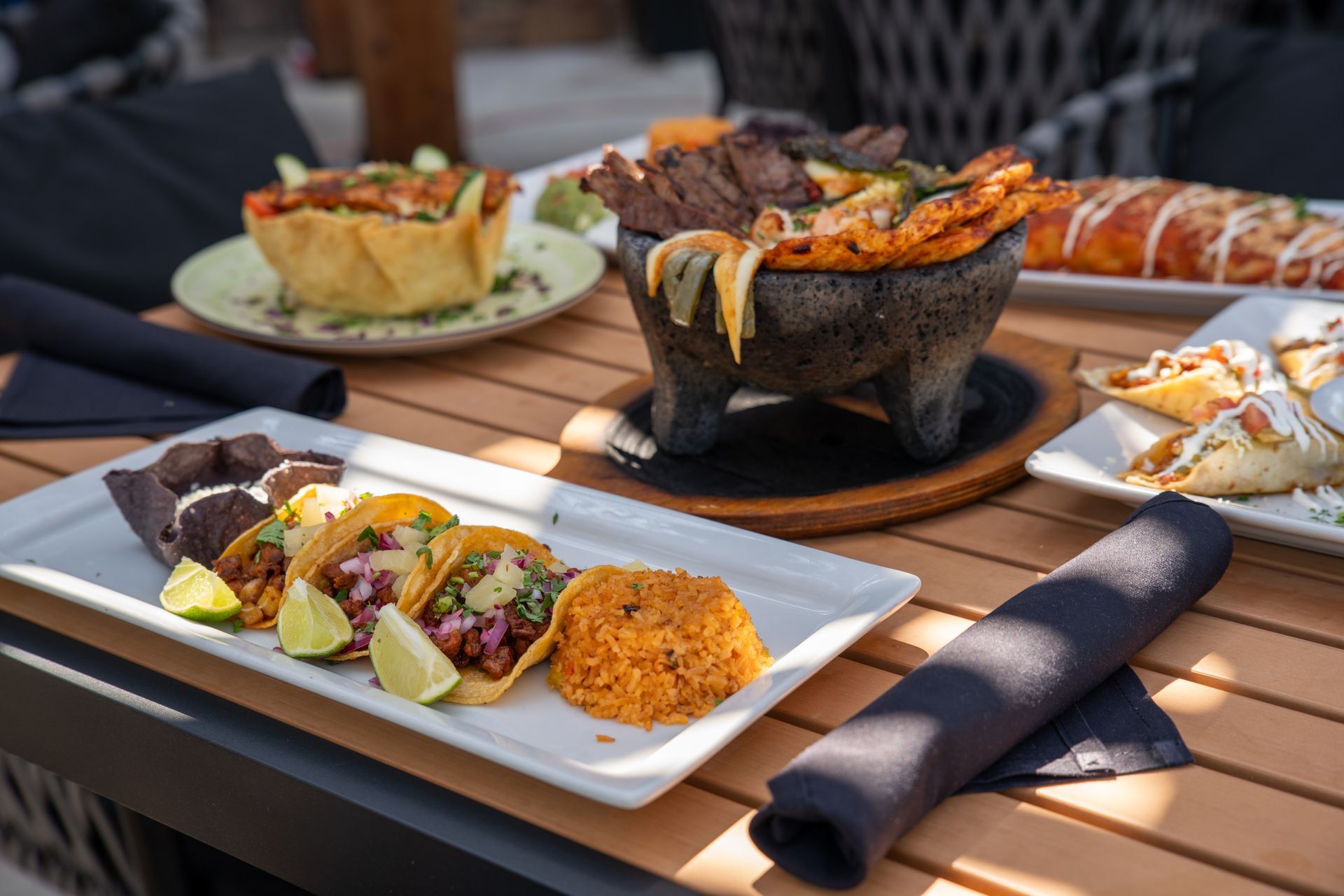 Mexican food spread on a table: tacos, fajitas, rice, and a baked dish.