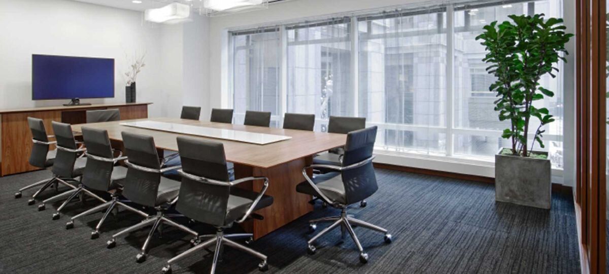 A conference room with a long table and chairs and a television.