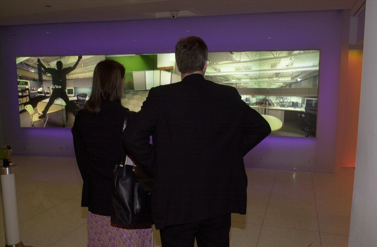 A man and a woman are looking at a large screen