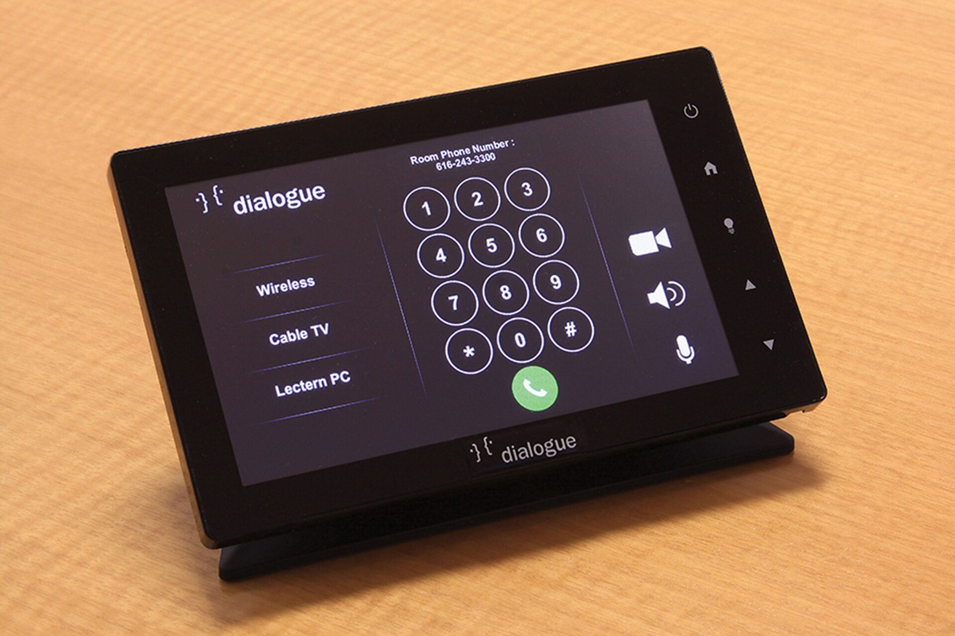 A black tablet is sitting on a wooden table.