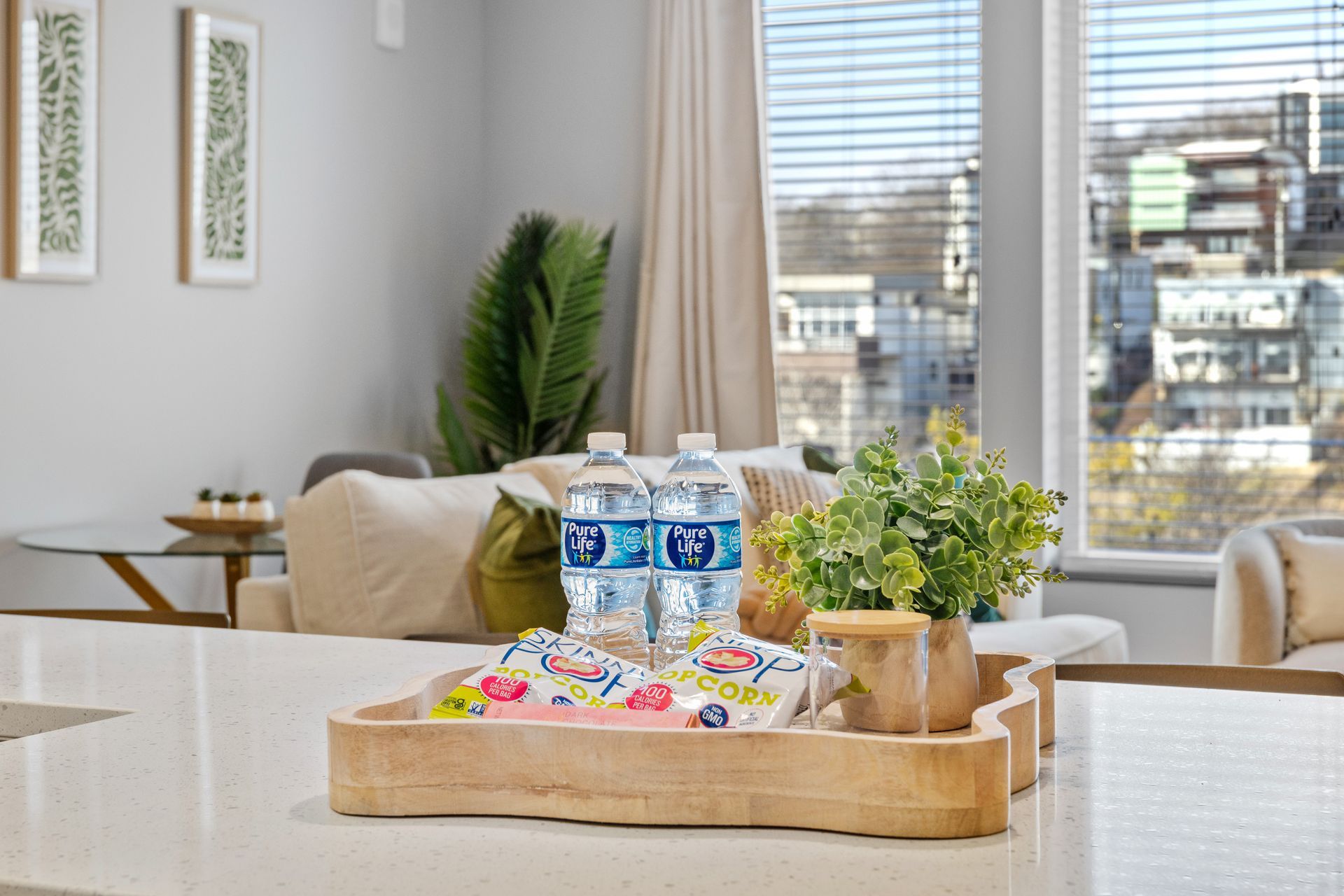 A wooden tray with water bottles on it is on a table in a living room.