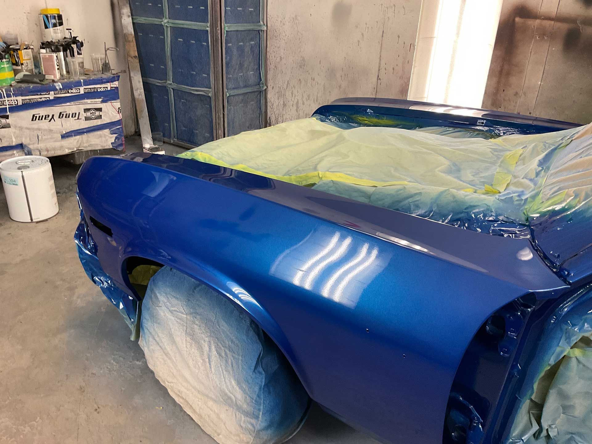A car is being painted blue in a garage