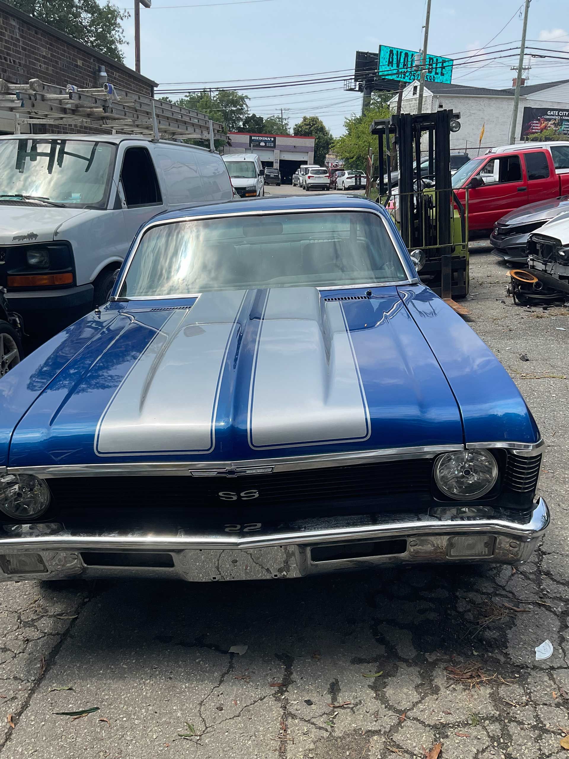 A blue and silver classic car is parked in a parking lot