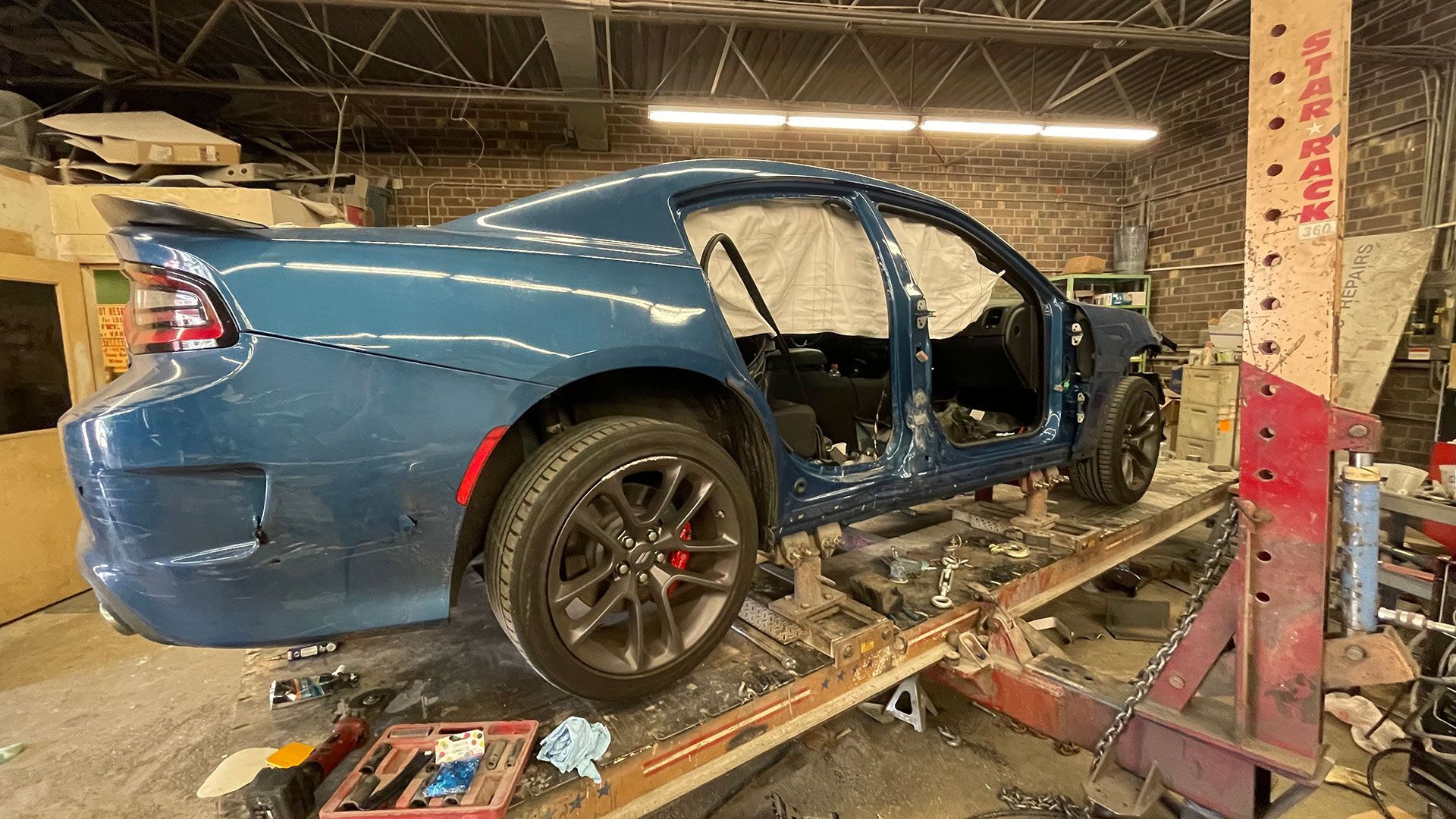 A blue vehicle is sitting on a lift in a garage
