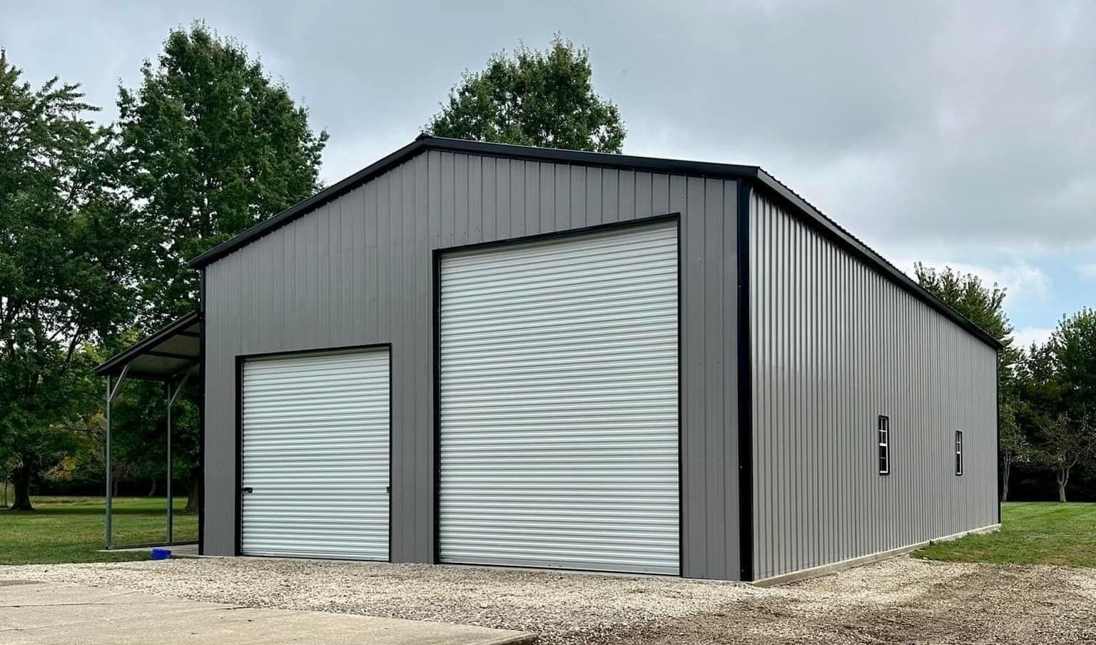 A metal garage with a white garage door and a black roof.