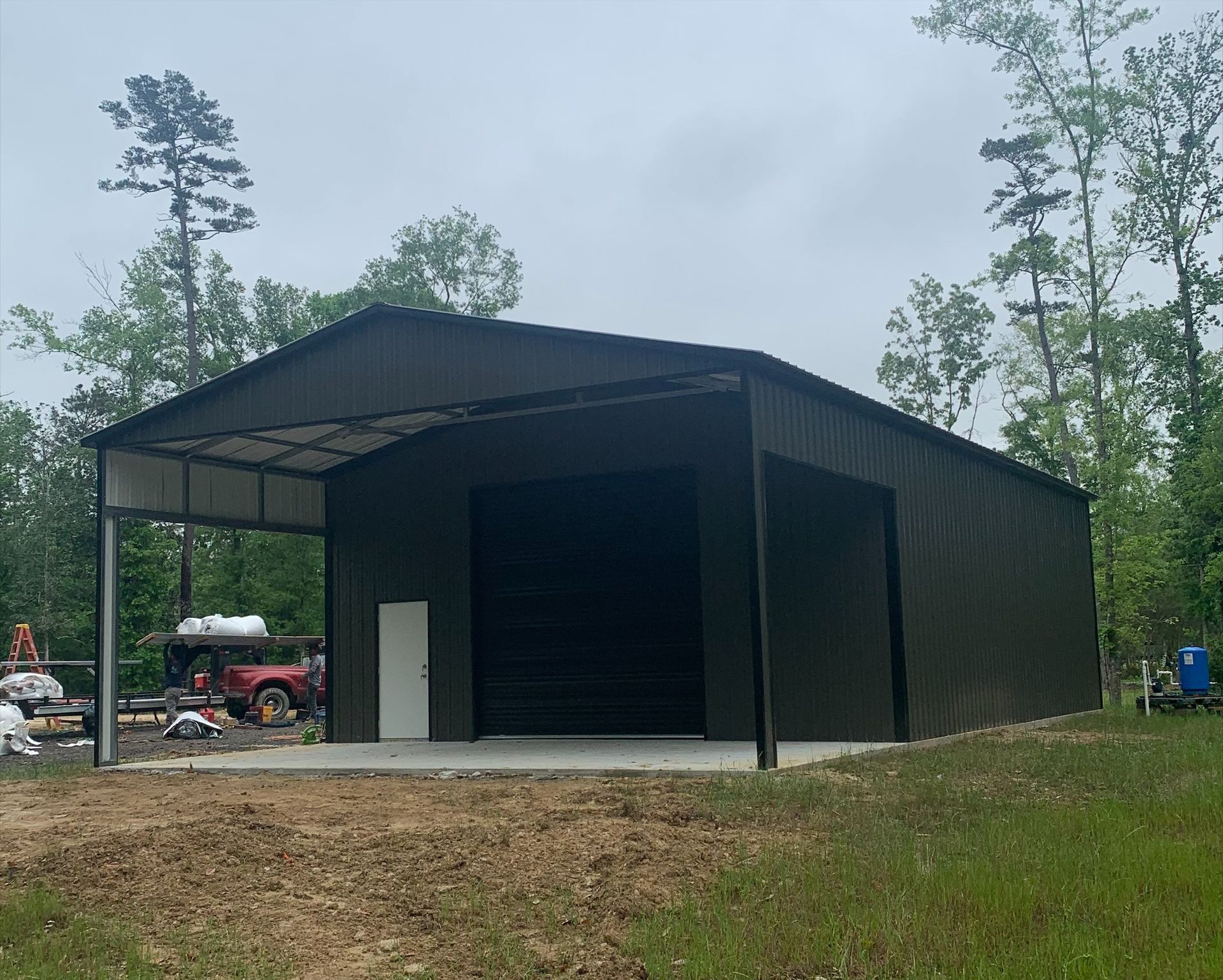 A large metal building is sitting in the middle of a grassy field.