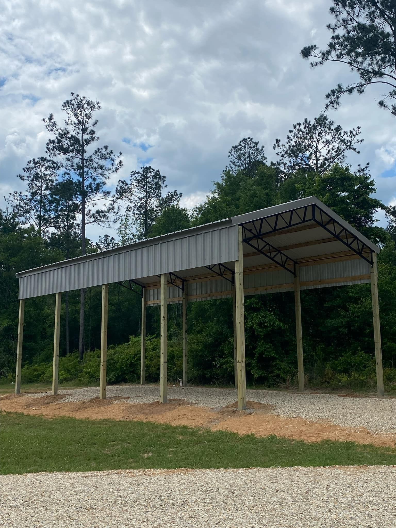 A carport is being built in the middle of a grassy field.