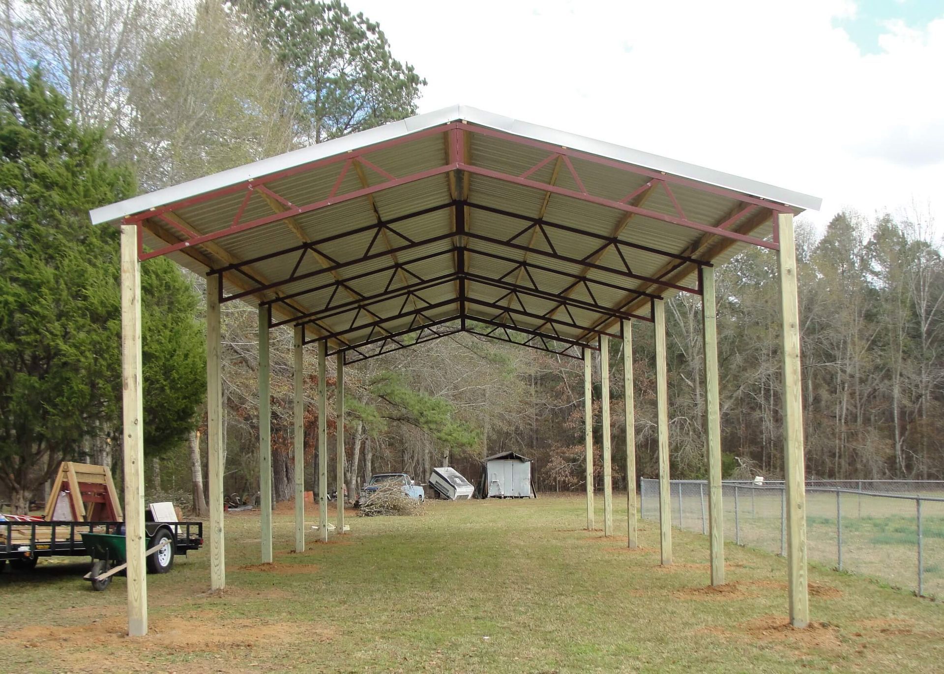 A carport is being built in the middle of a grassy field.